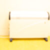 Sleek white convection heater against a soft yellow wall, enhancing warmth and comfort in homes.