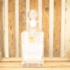 Elegant crystal decanter with ornate stopper on rustic wooden backdrop, perfect for special occasions.