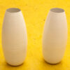 Elegant white vases on a vibrant yellow surface, highlighting modern minimalism and artistic design.