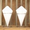 Elegante witte keramische kegels in moderne metalen houders op een rustieke houten achtergrond.