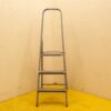 Eenvoudige grijze metalen ladder tegen beige muren in een functionele ruimte voor tweedehands producten.