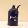 Vintage cobalt blue petroleum canister with gothic lettering and cork cap, showing signs of wear.
