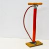 Vintage red bicycle pump with wooden handle, ideal for cycling enthusiasts and retro collectors.