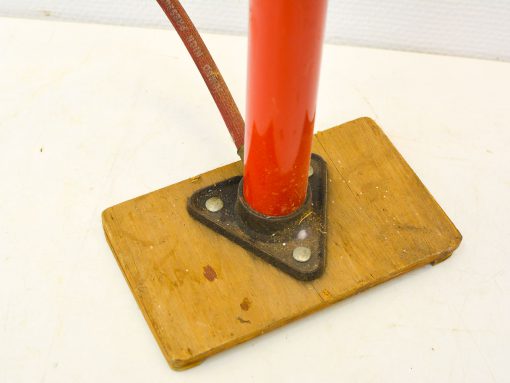 Vibrant red pole on a weathered wooden base, perfect for outdoor use and visibility.