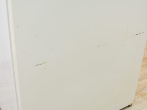 White vintage refrigerator with charming wear, adding character to a cozy kitchen atmosphere.