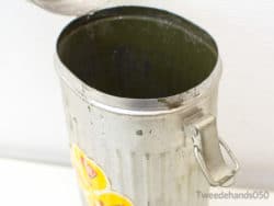 Charming vintage metal trash can with floral sticker, ideal for nostalgic home decor.