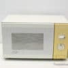 Charming vintage cream microwave with elegant gold knobs, ideal for retro kitchen aesthetics.