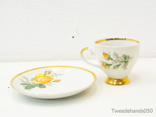 Elegant porcelain teacup and saucer with yellow rose design and gold accents for refined occasions.