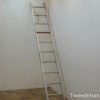 Sleek aluminum ladder against a white wall, enhancing a minimalist space with warm wooden flooring.