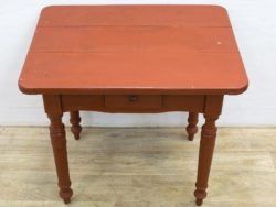 Charming vintage red table with drawer and elegant legs, perfect for cozy dining spaces.