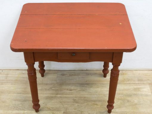 Charming vintage red table with drawer and elegant legs, perfect for cozy dining spaces.