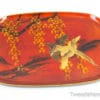 Elegant red tray featuring a graceful bird and vibrant floral decorations for stylish serving.