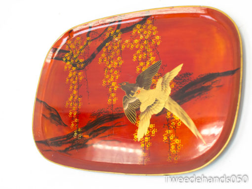 Stylish red decorative plate featuring a soaring bird and elegant yellow flowers.
