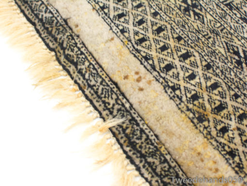 Vintage geometric rug with unique patterns and fringe, adding character to any interior space.