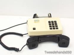 Vintage cream and black telephone with coiled cord, ideal for nostalgic decor and collectors.