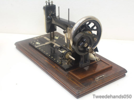 Elegant antique black sewing machine on wooden base, showcasing vintage craftsmanship and unique design.