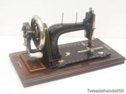 Vintage black sewing machine with gold accents on a wooden base, ideal for retro decor.