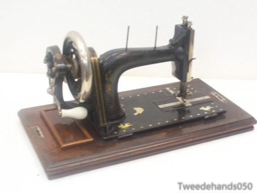 Vintage black sewing machine with gold accents on a wooden base, ideal for retro decor.