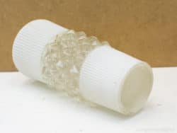 Vintage glass dispenser with diamond texture and ribbed white caps for elegant display.