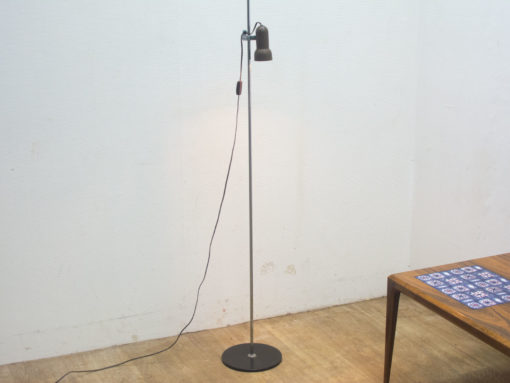 Modern floor lamp and wooden table enhance a cozy reading nook in a stylish room.