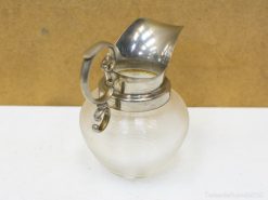 Elegant vintage glass pitcher with a metallic spout and handle, ideal for serving or decor.