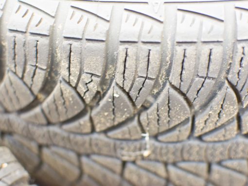 Close-up of a worn tire highlighting cracks and tread wear, essential for safe driving.