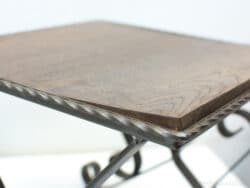 Elegant dark wood side table with artistic wrought iron base for stylish interiors.