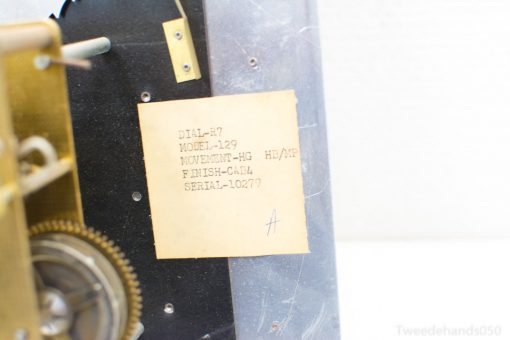 Vintage mechanical clock showcasing detailed golden gears and specifications label, serial number 10279.