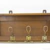 Elegant dark wood coat rack with brass hooks, perfect for vintage-inspired entryway organization.