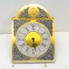 Elegant gold wall clock with Roman numerals and floral designs, perfect for timeless interiors.
