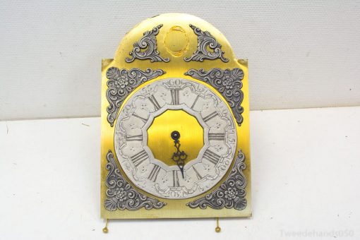 Elegant gold wall clock with Roman numerals and floral designs, perfect for timeless interiors.