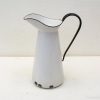 Charming vintage white pitcher with black handle, perfect for decor and daily use.