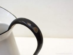 Elegant vintage enamel pitcher with charming black handle, perfect for decor or everyday use.