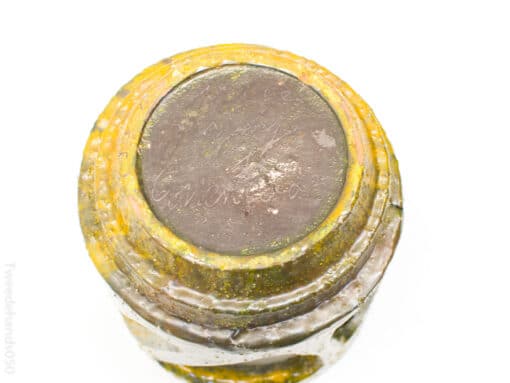 Vintage glass jar with yellow rim, showcasing unique texture and historical charm for collectors.