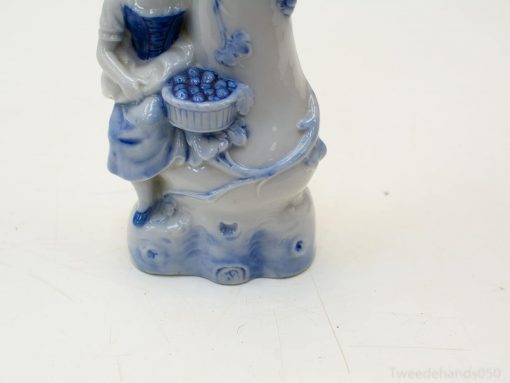Elegant porcelain woman figurine with blue and white details, holding a basket of berries.