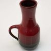 Elegant deep red ceramic pitcher with a glossy finish and graceful handle, perfect for decoration.