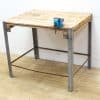 Rustic vintage workbench with metal legs and blue vise, ideal for woodworking and crafting projects.