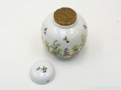 Charming porcelain jar with floral designs and cork lid, perfect for home decor accents.