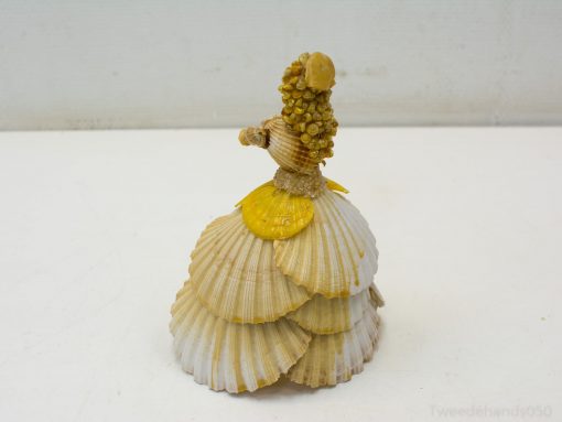 Elegant seashell figurine of a lady in a layered dress, showcasing intricate coastal artistry.