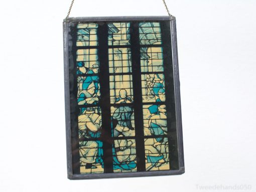 Colorful stained glass panel depicting historical scenes in rich blues and creams.