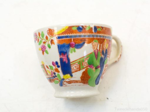 Elegant hand-painted porcelain cup featuring vibrant figures and floral designs, a charming collectible piece.