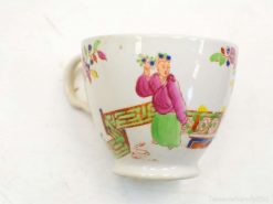 Colorful porcelain cup depicting a traditional woman and floral elements, ideal for decorative settings.