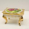 Elegant vintage trinket box featuring a colorful pastoral scene and luxurious gold accents.