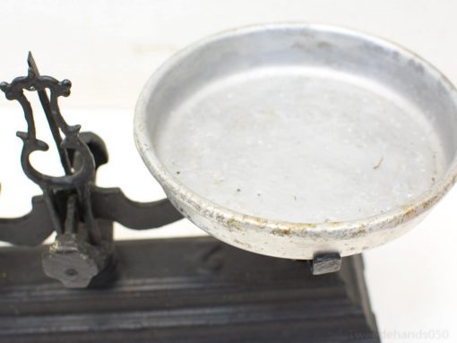 Vintage balance scale with cast iron base and aluminum pan, showcasing timeless craftsmanship.
