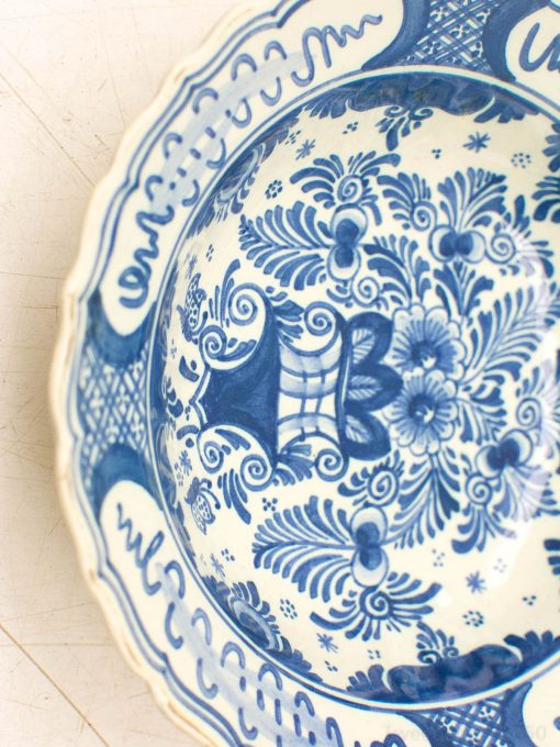 Elegant blue and white ceramic bowl with floral designs and scalloped edge, perfect for decor.