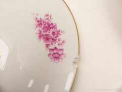 Vintage porcelain plate with pink roses and gold trim, featuring a charming history-rich chip.