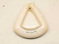 Triangular porcelain decoration with West India inscription, featuring a glossy finish and hanging wire.