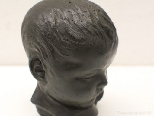 Realistic black ceramic sculpture of a childs head, embodying innocence and nostalgia.