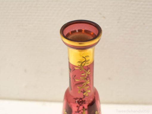 Elegant ruby red vase with gold rim and floral patterns, perfect for stylish decor and flowers.