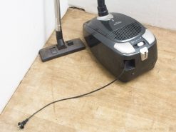 Compact black vacuum cleaner with silver accents, designed for efficient and versatile cleaning.